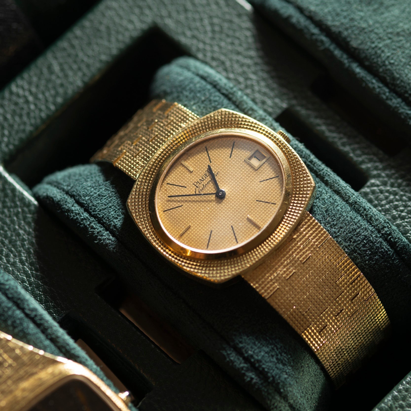Piaget Yellow Gold Hobnail Dress Watch with a textured band displayed on a dark green watch case.