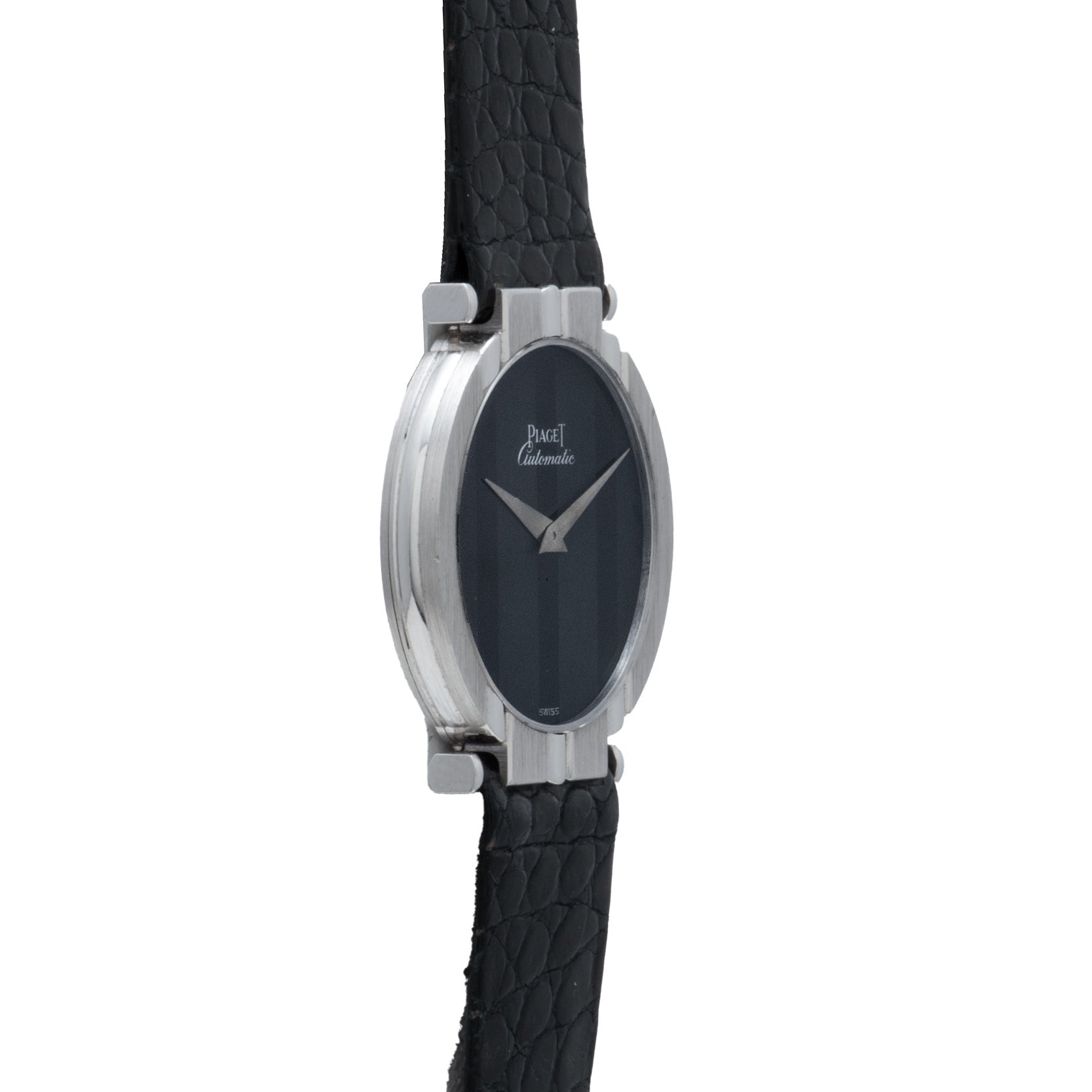A white gold oval ladies watch by Piaget, featuring a leather strap, silver casing, and a minimalist black dial.