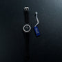A Piaget White Gold Ladies wristwatch with a silver case is shown beside a blue tag labeled Piaget on a dark surface.