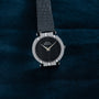 A Piaget White Gold Ladies wristwatch rests on a dark blue textured surface.