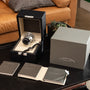 A Lange & Sohne Langematik Perpetual Calendar watch is displayed in its box with manuals and packaging on a coffee table by a sofa.