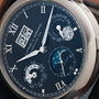 Close-up of a luxury Lange & Sohne Langematik Perpetual Calendar watch featuring time, date, day, month, and moon phase on a dark dial.