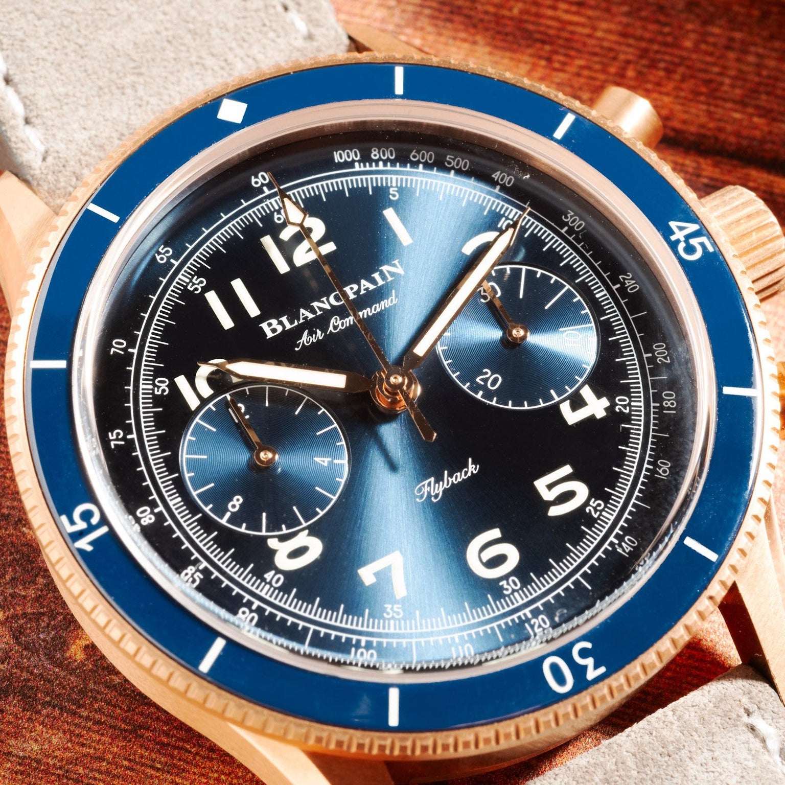Close-up of the Blancpain Air Command Flyback Chronograph featuring a blue dial, gold case, white numerals, and a leather strap.