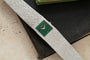 A Piaget White Gold Malachite Dress Watch with a green square face rests atop two closed books.