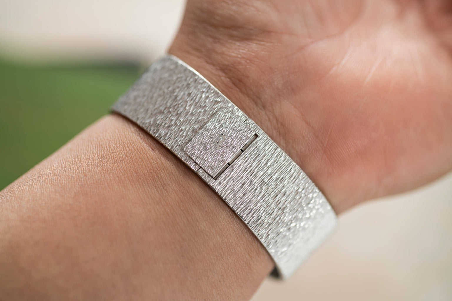 A close-up of a wrist wearing the Piaget White Gold Malachite Dress Watch, featuring a minimalist square face.