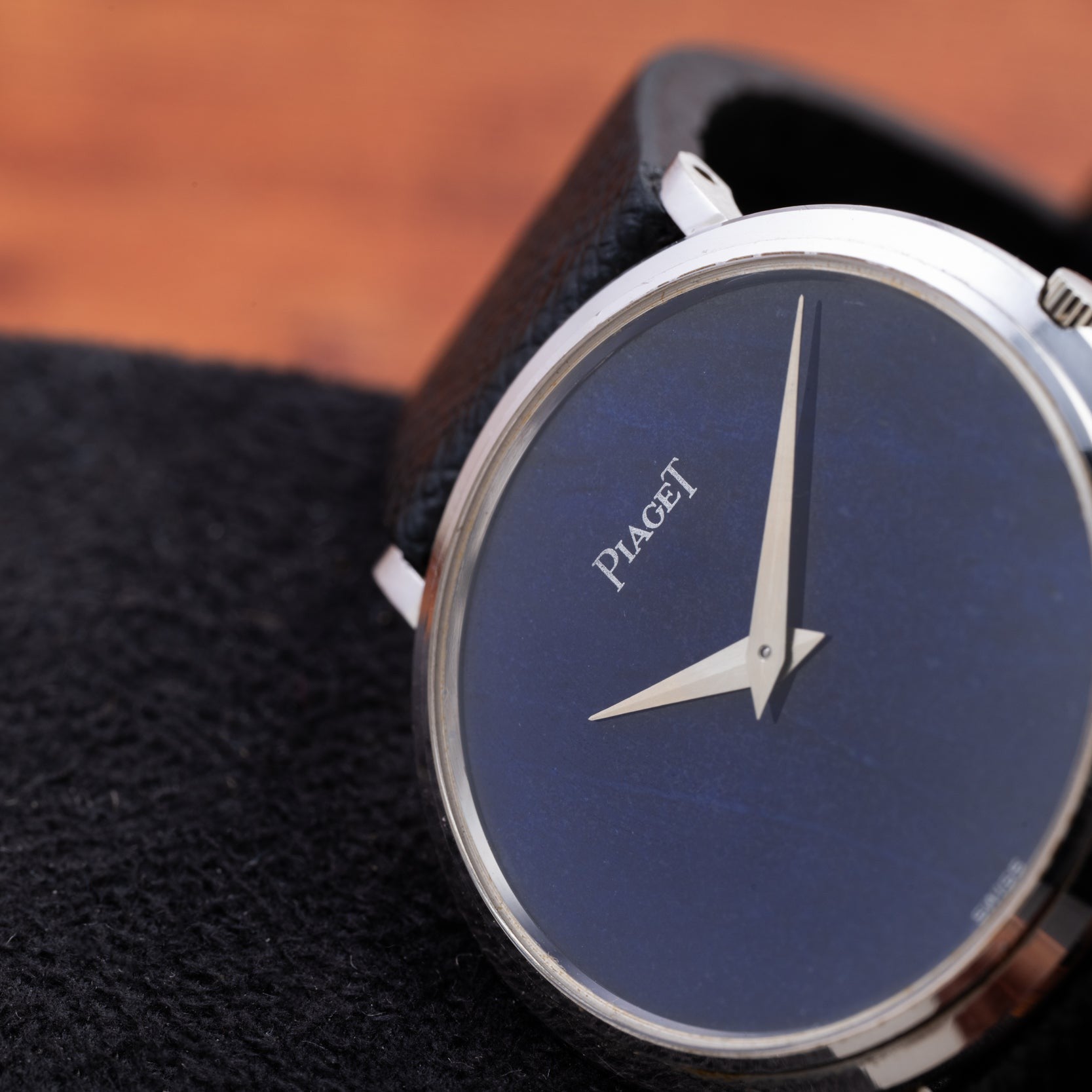 Close-up of the Piaget Ladies Lapis Lazuli Dress Watch, featuring a blue lapis lazuli dial and silver hands, displayed on a black textured surface.