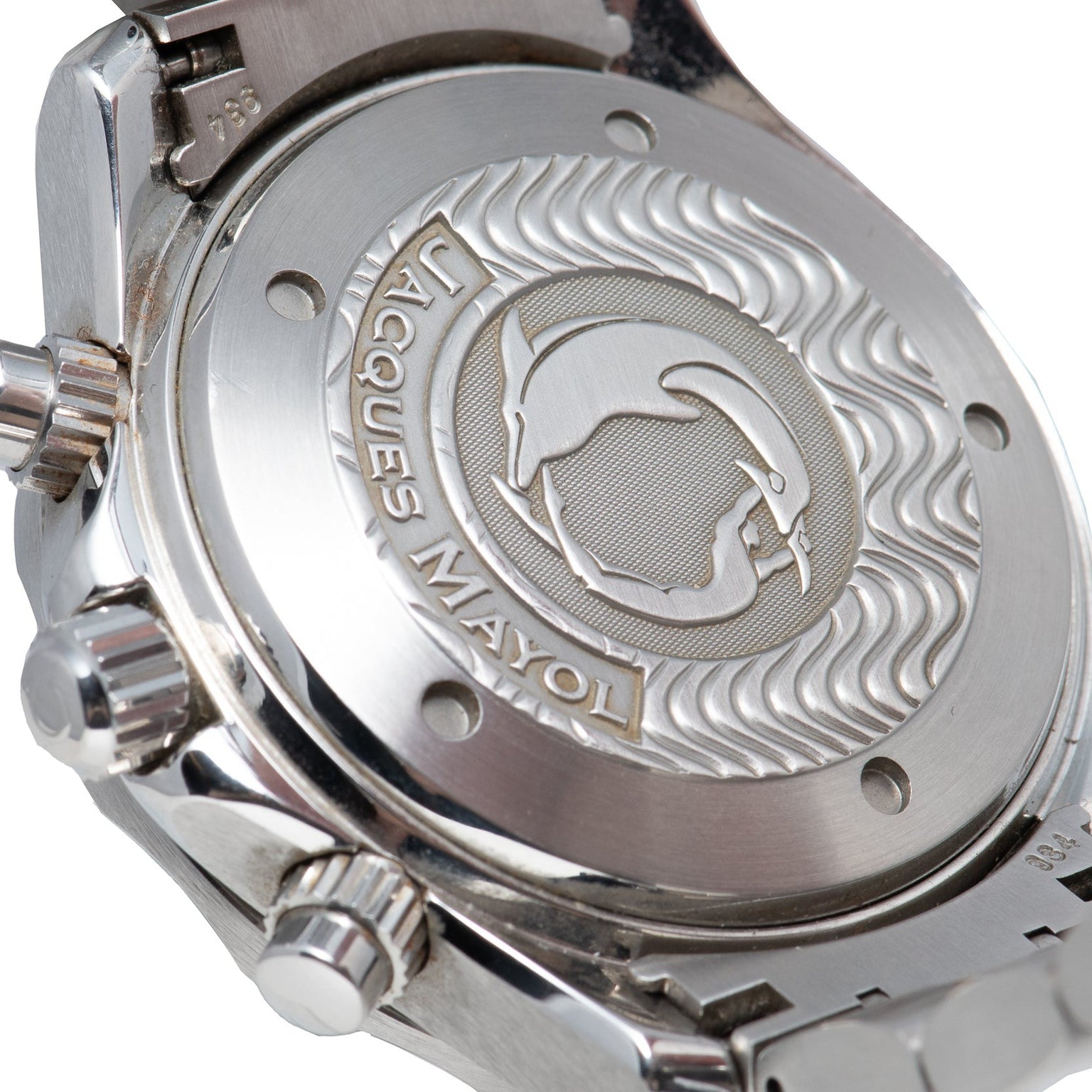 Close-up of the OMEGA Seamaster 300 Professional Apnea Chronograph’s case back, engraved with a dolphin, wave patterns, and Jacques Mayol’s name.