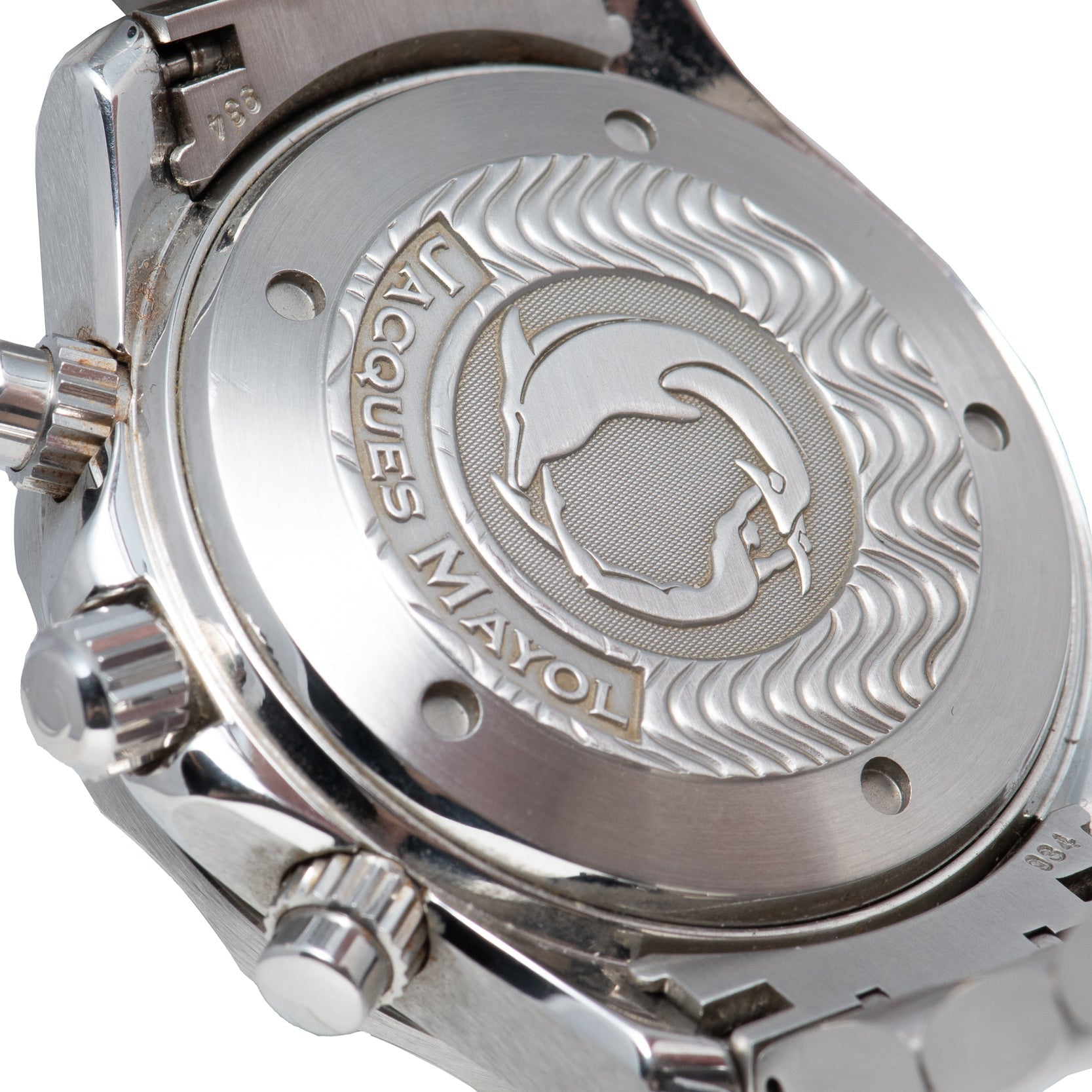 Close-up of the OMEGA Seamaster 300 Professional Apnea Chronograph’s case back, engraved with a dolphin, wave patterns, and Jacques Mayol’s name.