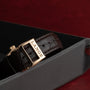 Close-up of a brown leather strap with a gold buckle engraved LANGE, part of the Lange & Sohne Lange 1 Tourbillon, displayed on a dark tray.