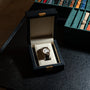 The Lange & Sohne Lange 1 Tourbillon luxury wristwatch is presented in a black display box next to a case of assorted watch straps on a dark table.