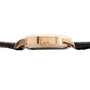 Side view of the Lange & Sohne Lange 1 Tourbillon gold case with a black leather strap and visible crown.