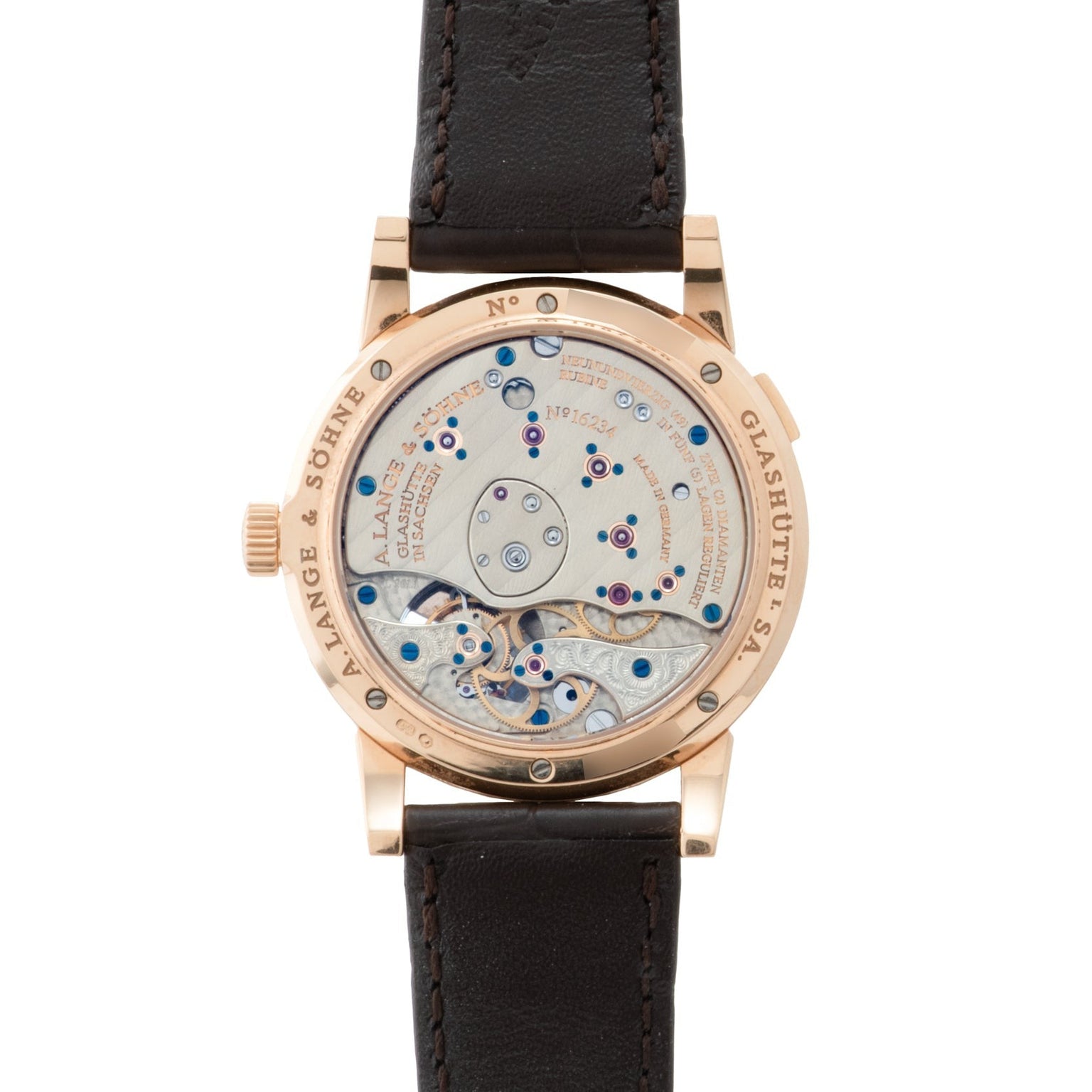 The Lange & Sohne Lange 1 Tourbillon is a luxury watch featuring a visible mechanical movement and a brown leather strap, shown from the back.