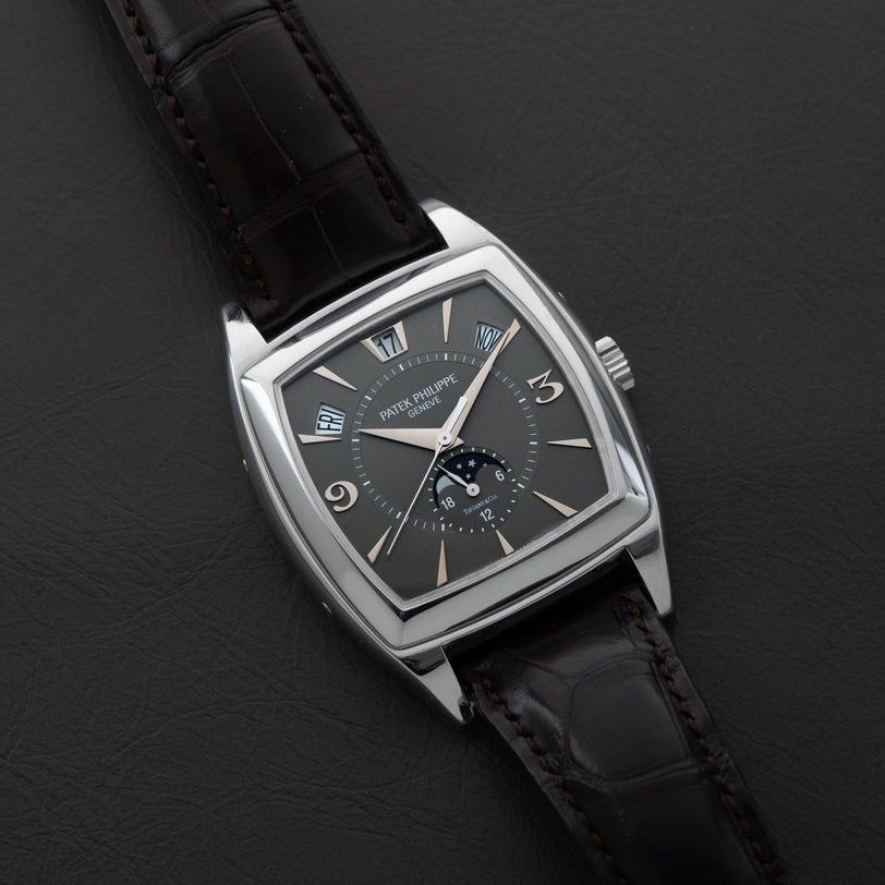 The Patek Philippe Gondolo Annual Calendar features a square black dial and a black leather strap, elegantly displayed on a dark surface.