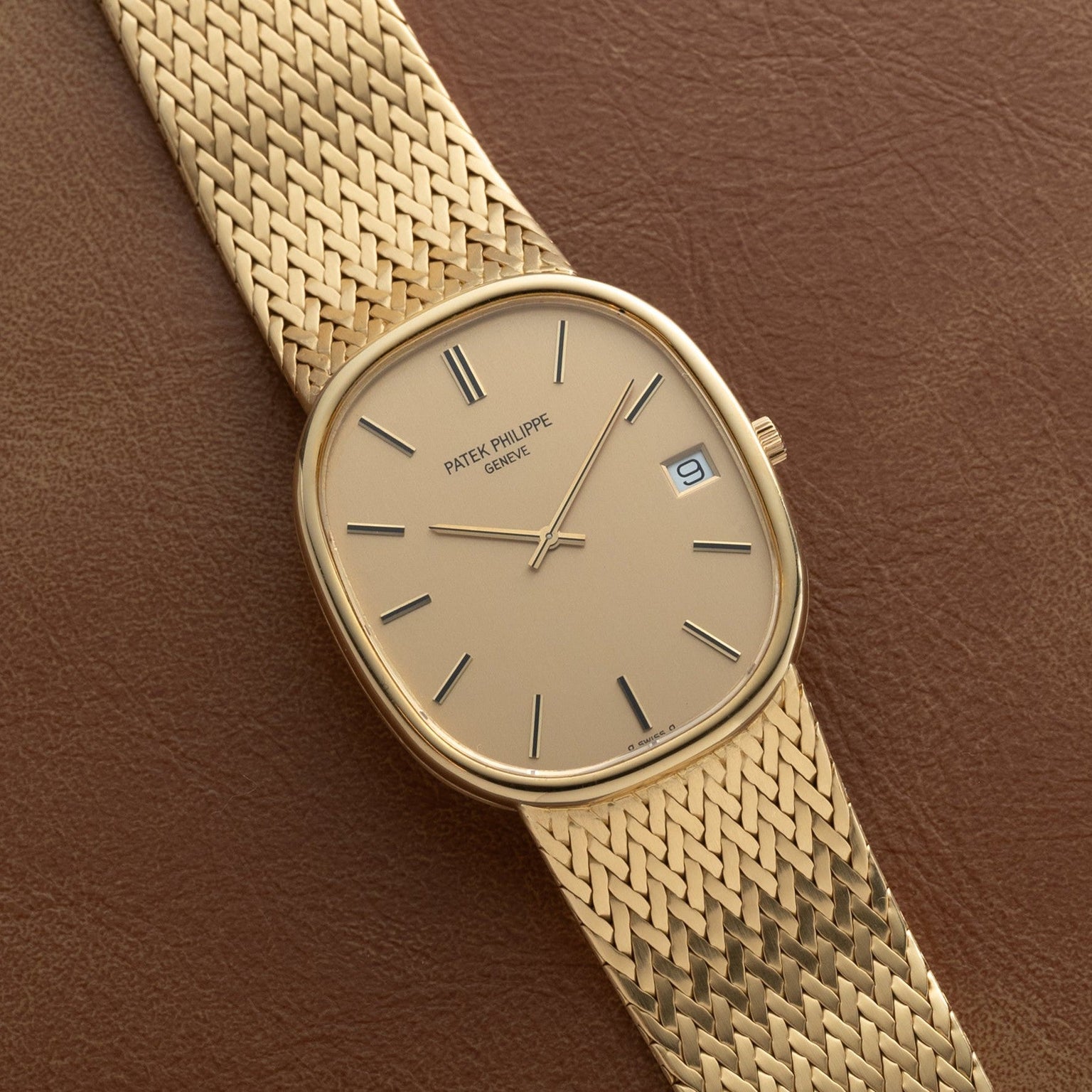 Patek Philippe Ellipse Jumbo with mesh band and date display, shown on a brown leather surface.