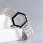 The Piaget Hexagonal Diamond Dress Watch features a woven silver band, elegantly displayed on a white marble surface.