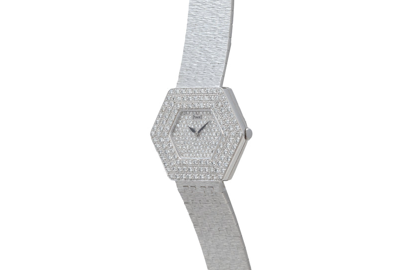 The Piaget Hexagonal Diamond Dress Watch features a silver case with diamond accents and a textured metal band, displayed on a white background.