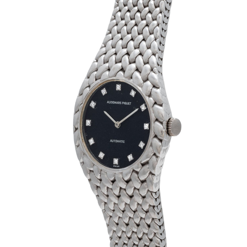 The Audemars Piguet Cobra is a silver wristwatch with a black face, diamond hour markers, and a textured metal band.