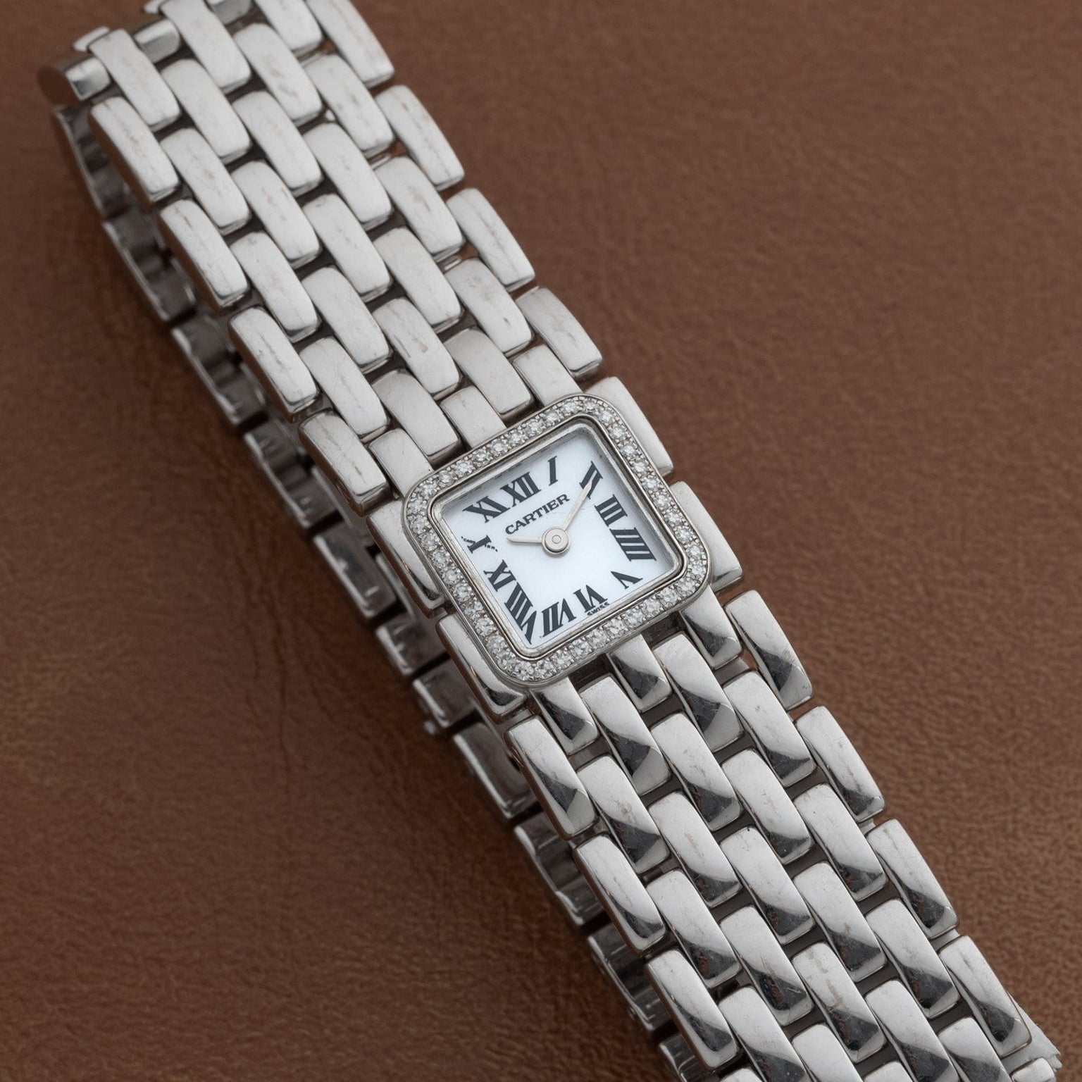 A Cartier Panthère Ruban Mother Of Pearl wristwatch featuring a square face and Roman numerals on a brown leather strap.