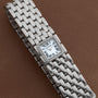A Cartier Panthère Ruban Mother Of Pearl wristwatch featuring a square face and Roman numerals on a brown leather strap.