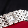 Close-up of the Cartier Panthère Ruban Mother Of Pearl watch with a silver band and diamond bezel, resting on a red surface.