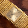 The Piaget Emperador quartz watch with a textured bracelet rests on a wooden surface.