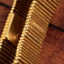 Close-up of the Piaget Emperador gold-toned metal watch band, featuring a textured, wood-like pattern, displayed on a wooden surface.