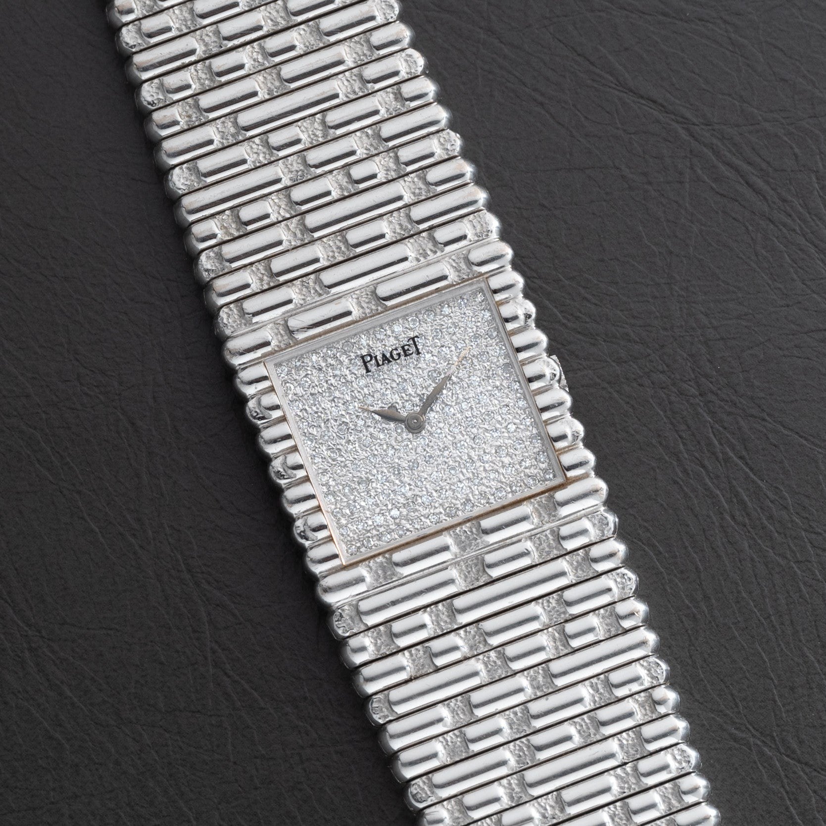 A Piaget Emperador Diamond wristwatch with a textured square dial and matching silver bracelet displayed on a black surface.