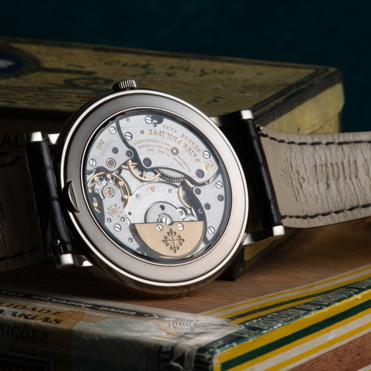 A close-up of the intricate inner mechanism of the Patek Philippe Perpetual Calendar Moonphase wristwatch displayed on a vintage book.