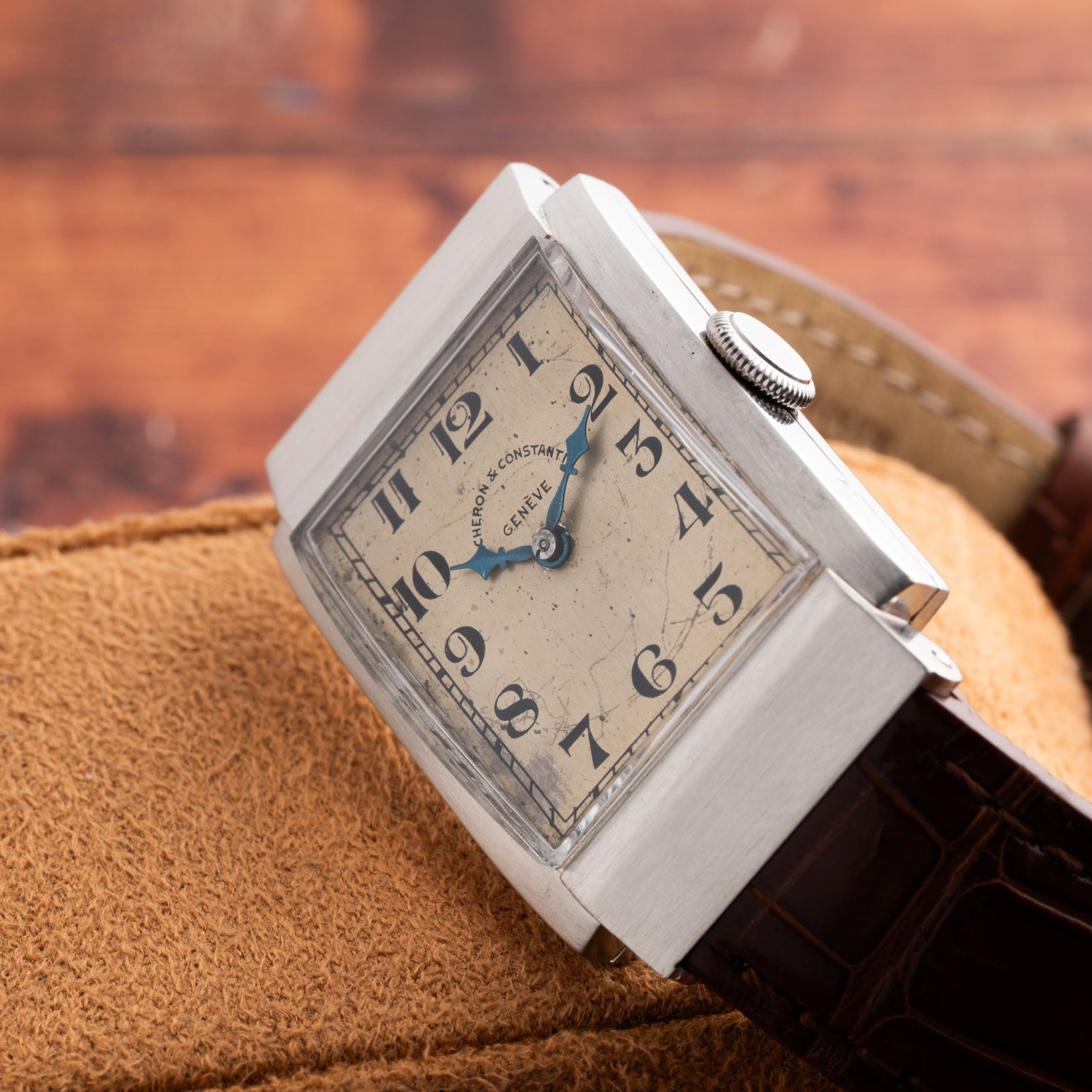 A Vacheron Constantin Rectangular Steel Dress Watch with a leather strap rests on a tan suede surface.