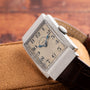 A Vacheron Constantin Rectangular Steel Dress Watch with a leather strap rests on a tan suede surface.