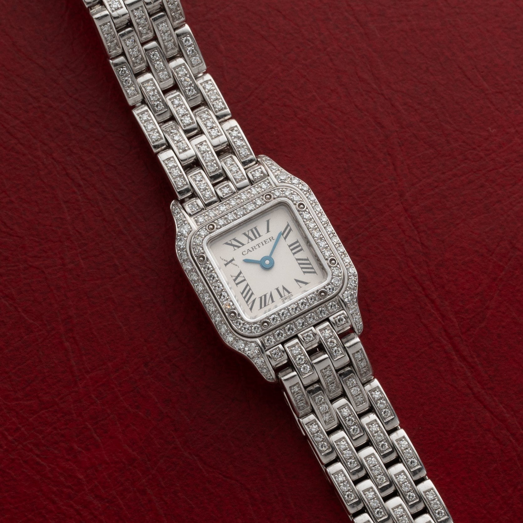 Cartier Panthère Diamond wristwatch with diamond accents displayed on a red textured background.