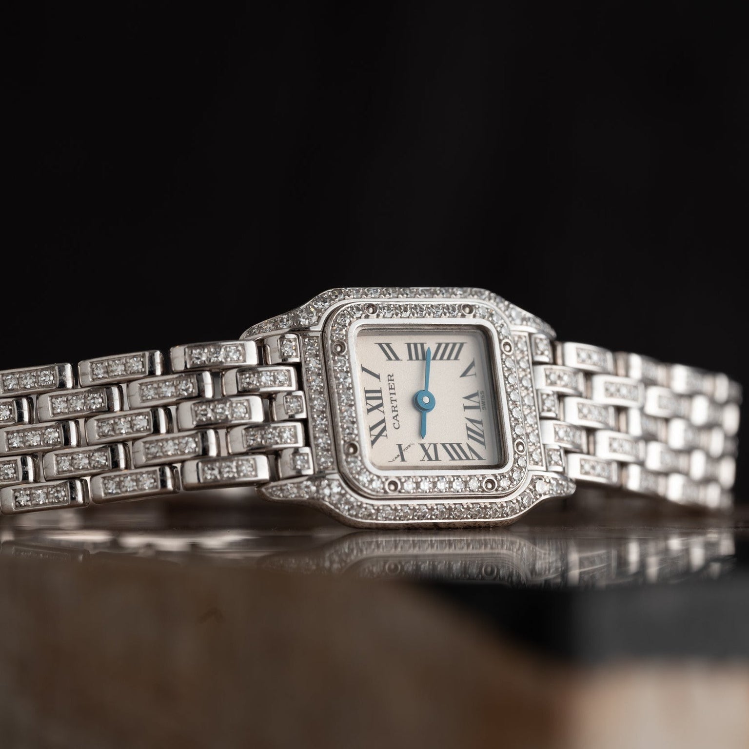 The Cartier Panthère Diamond is a wristwatch with a square face, Roman numerals, and diamond accents on a silver band.