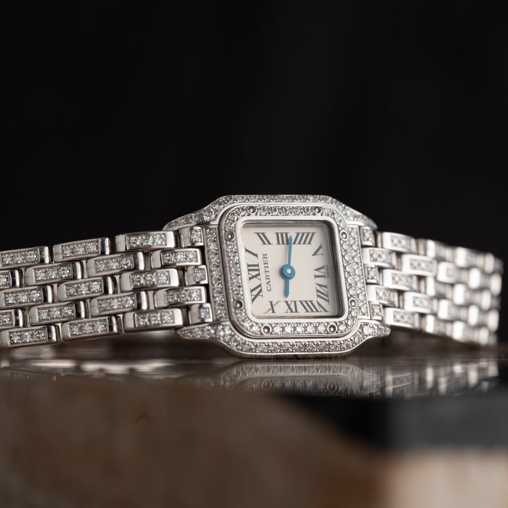 The Cartier Panthère Diamond is a wristwatch with a square face, Roman numerals, and diamond accents on a silver band.
