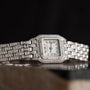 The Cartier Panthère Diamond is a wristwatch with a square face, Roman numerals, and diamond accents on a silver band.