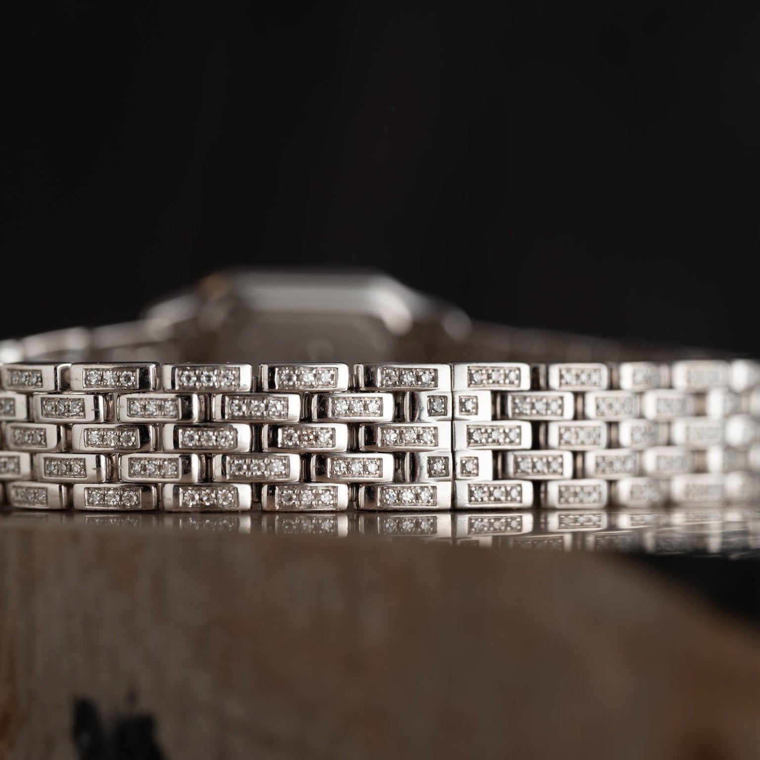 Close-up of the Cartier Panthère Diamond bracelet, featuring a silver geometric design adorned with small diamonds, set against a dark background.