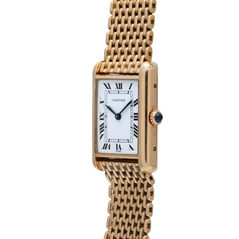 The Cartier Tank Louis watch features a rectangular face with Roman numerals and a gold mesh bracelet, shown on a white background.