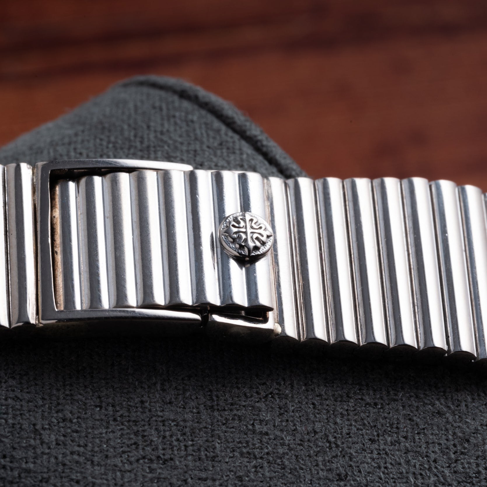 Close-up of the silver, ridged metal band of the Patek Philippe Ellipse Gondolo Onyx watch, featuring an ornate round detail on textured dark fabric.