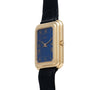 The Piaget Tank Blue Lapis is a rectangular gold watch with a blue face, Roman numerals, and a black leather strap, shown from an angle.