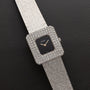 The Piaget Onyx Diamond Dress Watch features a square design with diamond accents and a textured silver band, displayed on black leather.