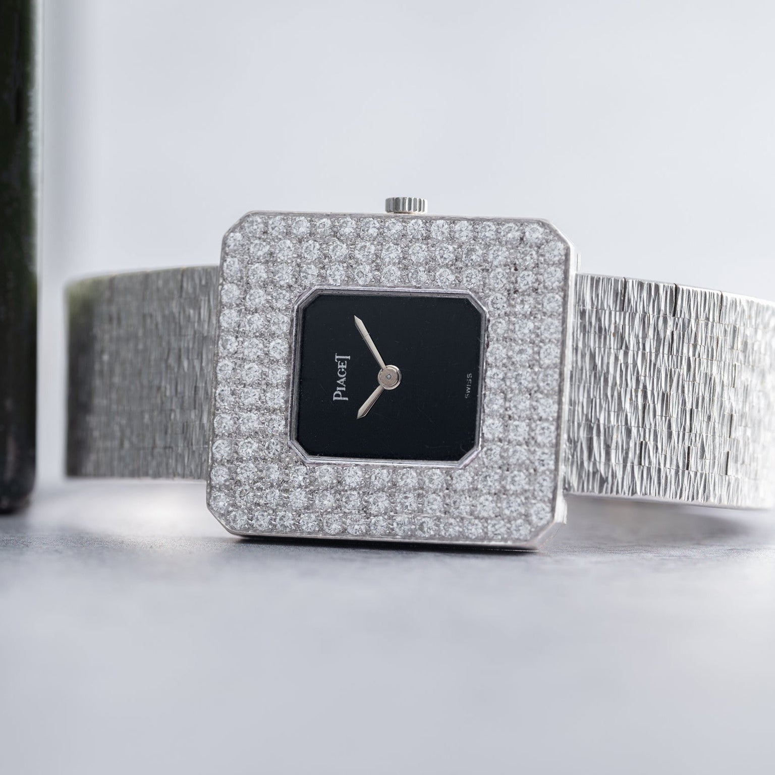The Piaget Onyx Diamond Dress Watch features a diamond-encrusted square bezel and a textured silver band for a luxurious look.