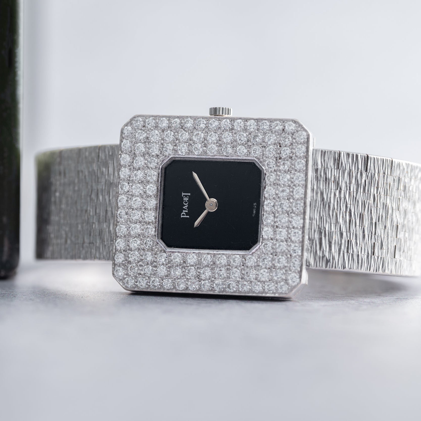 The Piaget Onyx Diamond Dress Watch features a diamond-encrusted square bezel and a textured silver band for a luxurious look.