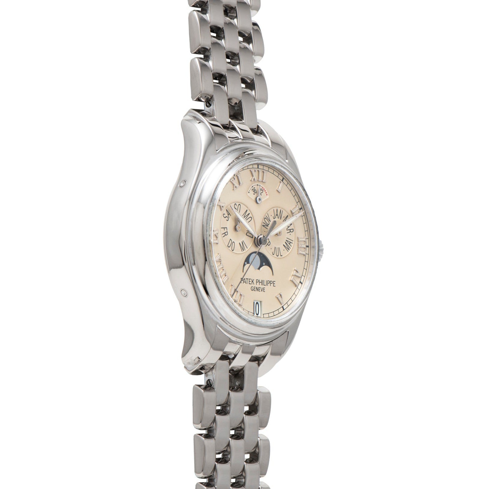 The Patek Philippe Annual Calendar wristwatch features a silver case, beige dial with Roman numerals, and a linked metal band, displayed at an angle.