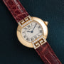 Cartier Ellipse watch with a red leather strap and diamond accents, displayed on a dark textured surface.