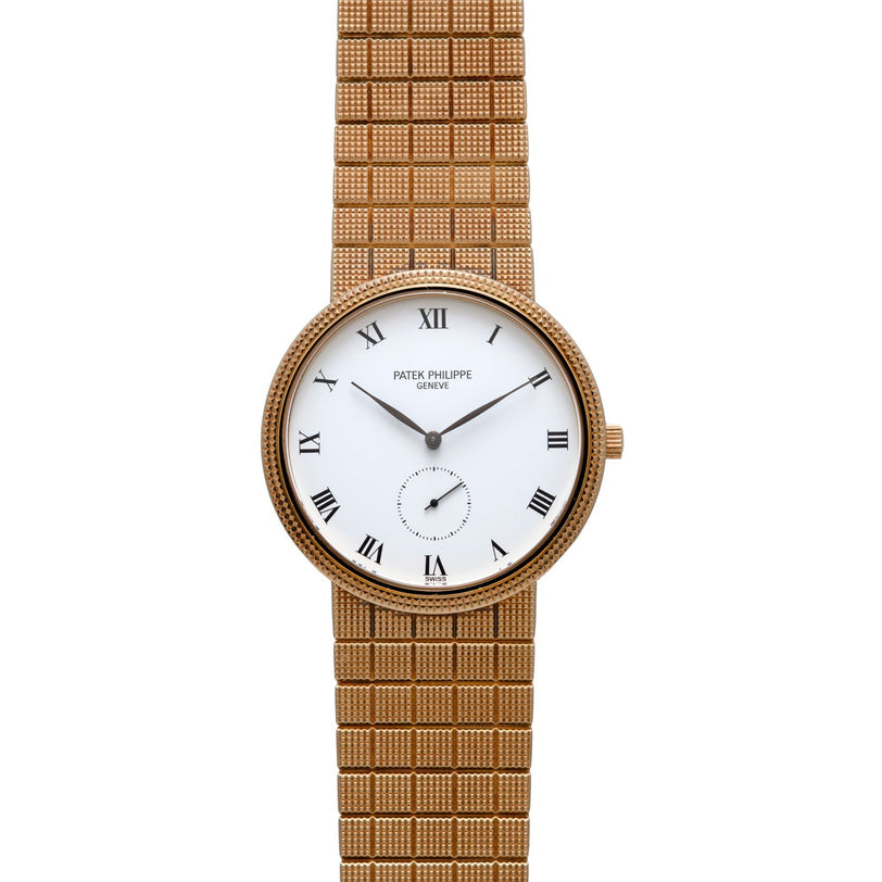 Patek Philippe Calatrava gold wristwatch featuring a white face, Roman numerals, and a patterned gold band.