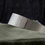 Close-up of the Piaget Sqound White Gold Dress Watch band displayed on textured green fabric.