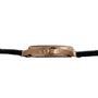 Side view of the Patek Philippe Aquanaut gold wristwatch featuring a black leather strap and a round crown.