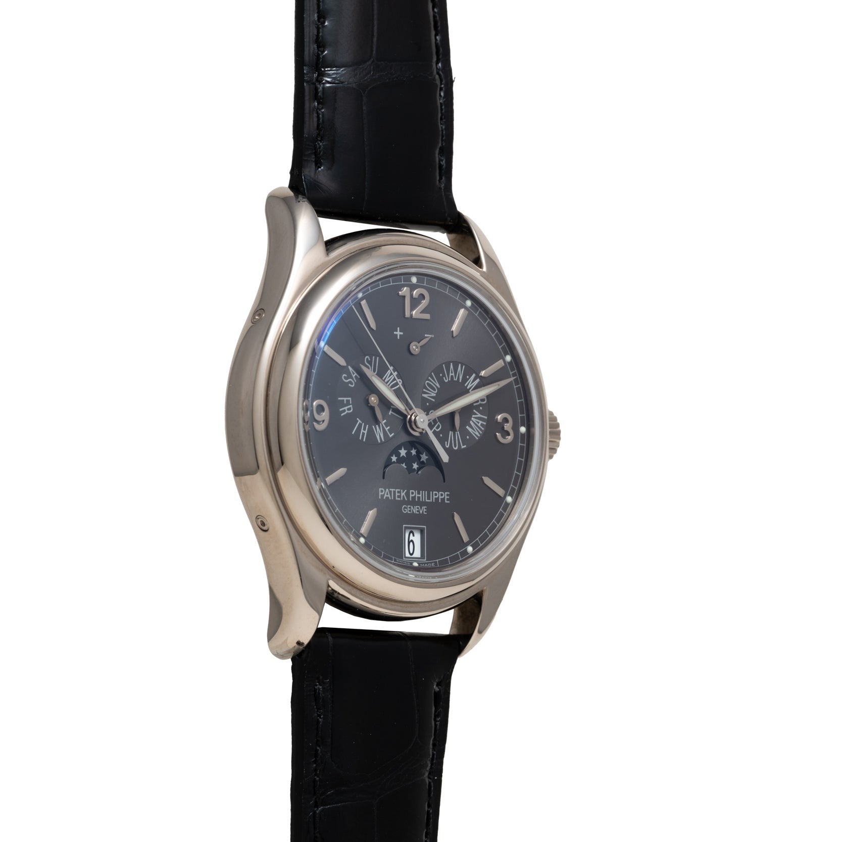 The Patek Philippe Annual Calendar Moonphase wristwatch features a silver case, black leather strap, and dark dial, shown at a slight angle.
