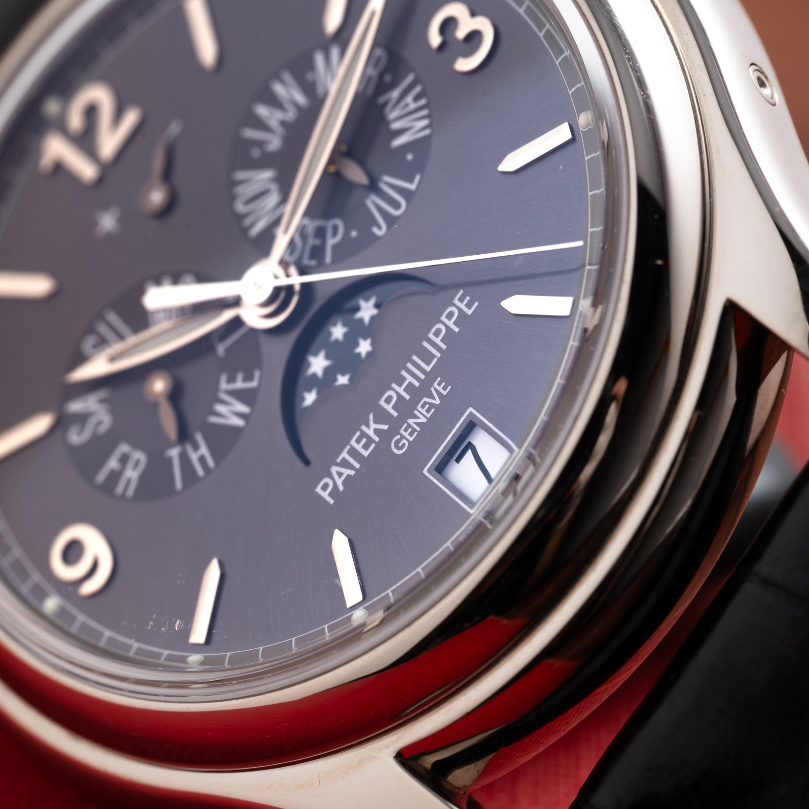 Close-up of a Patek Philippe Annual Calendar Moonphase watch face displaying date, day, month, and moon phase indicators.