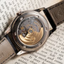 Close-up of a Patek Philippe Annual Calendar Moonphase watch’s exposed movement, resting on an open book with visible text.