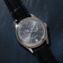 The Patek Philippe Annual Calendar Moonphase luxury wristwatch with a black leather strap is elegantly displayed on a dark textured surface.